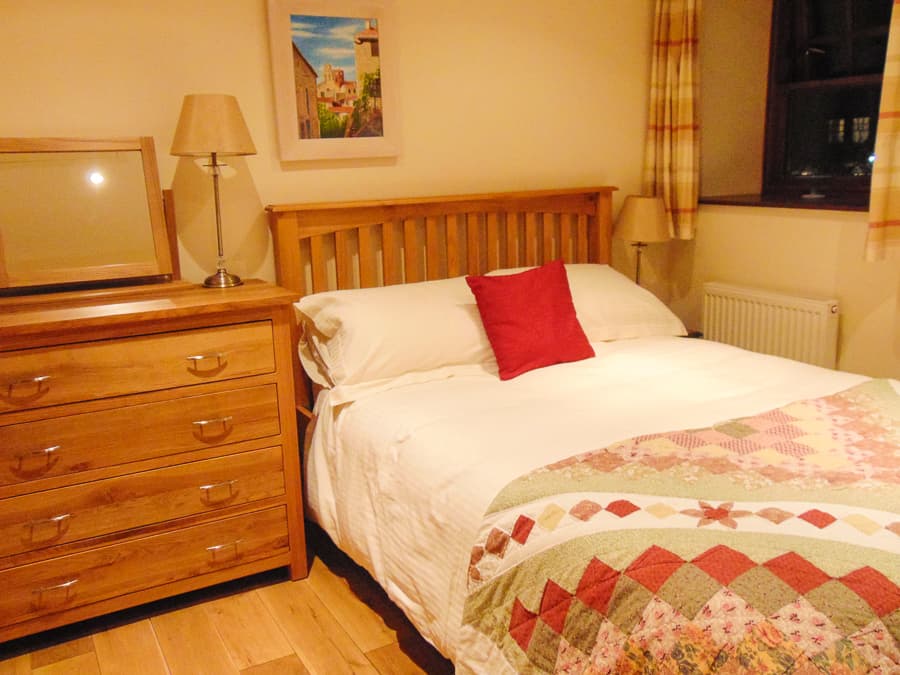 Double bedroom with oak furniture and patchwork quilt at Perthshire Courtyard