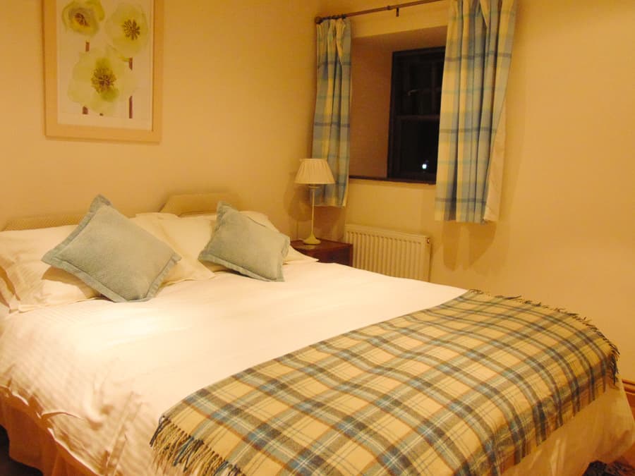 Double bedroom with tartan furnishings in a Perthshire Courtyard apartment