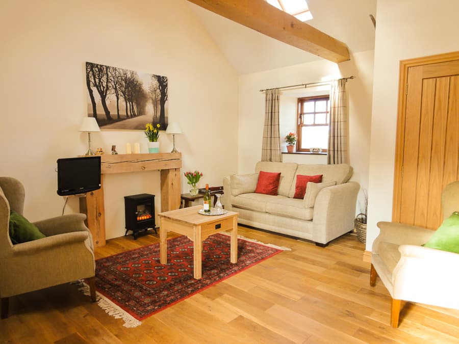 Apartment sitting room with wood-burning stove and oak flooring at Perthshire Courtyard
